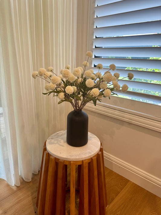 Black vase on stool with white faux flowers