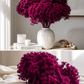 Fushia hydrangea in a white vase on a table and a bunch on the bed