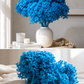 Vibrant Blue hydrangea in a white vale on a table and a bunch on the bed