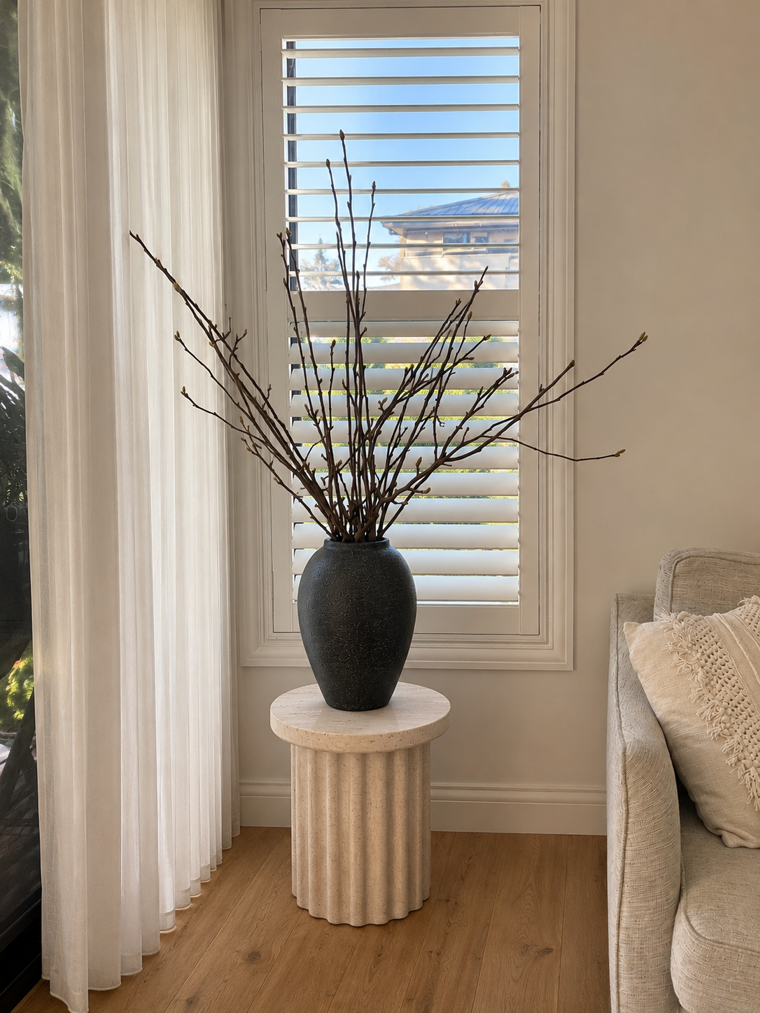 Decorative vase with branches on a small table in a living room setting.