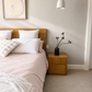 Neatly made bed with pink bedding and wooden headboard in a bedroom setting.