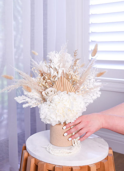 someone reaching to hold the dried flower arrangement