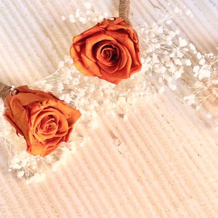 Single Deep Rust Orange Rose with cream babys breath arranged for use in suit button hole.